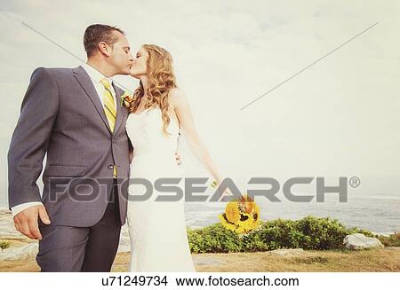 Picture - Portrait of married couple kissing, sea in background. Fotosearch