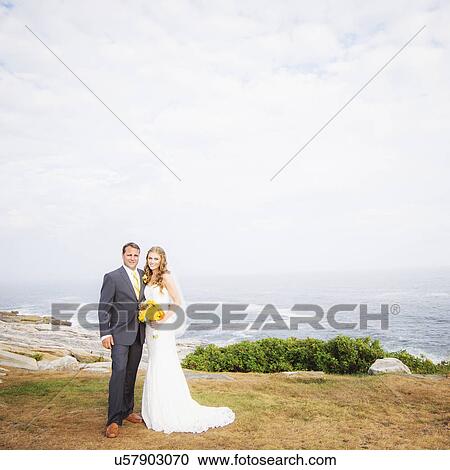 Stock Image - Portrait of married couple, sea in background. Fotosearch