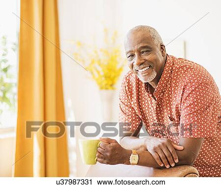 Stock Image - Portrait of men leaning on armchair, holding mug. Fotosearch