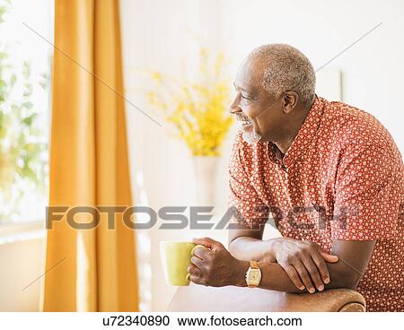 Stock Image - Portrait of men leaning on armchair, holding mug. Fotosearch