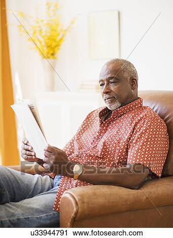 Stock Image - Portrait of men reading newspaper in armchair. Fotosearch