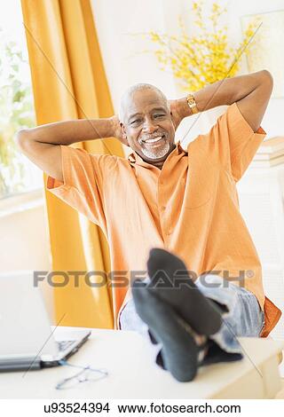 Picture - Portrait of men sitting with feet up. Fotosearch
