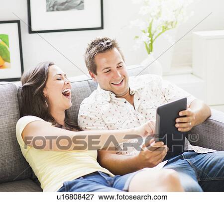 Portrait of playful couple using digital tablet on sofa View Large Photo Image Stock Photo - Portrait of playful couple using digital tablet on sofa. Fotosearch
