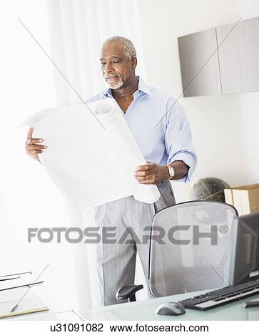 Stock Image - Portrait of senior man holding blueprint. Fotosearch