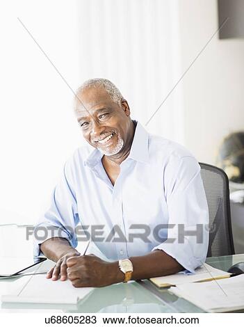 Stock Image - Portrait of senior man writing in office. Fotosearch