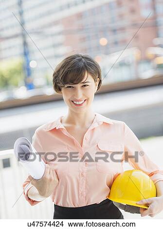 Portrait of smiling woman holding blueprints and hard hat View Large Photo Image Picture - Portrait of smiling woman holding blueprints and hard hat. Fotosearch