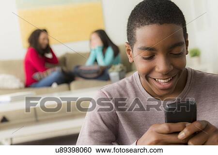 Stock Image - Portrait of teenage boy (14-15) with smartphone. Fotosearch