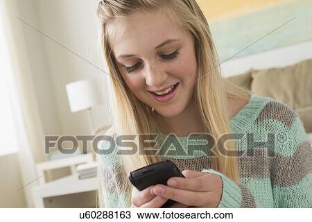 Stock Image - Portrait of teenage girl (14-15) with smartphone. Fotosearch