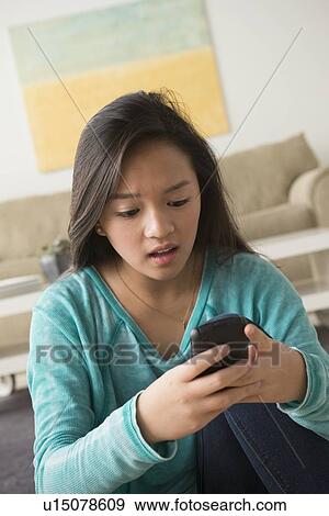 Stock Photo - Portrait of teenage girl (16-17) with smartphone. Fotosearch