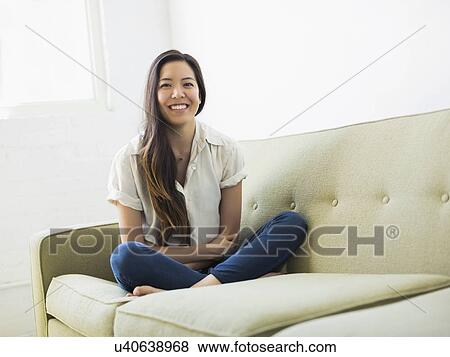 Stock Photo - Portrait of woman sitting on sofa. Fotosearch