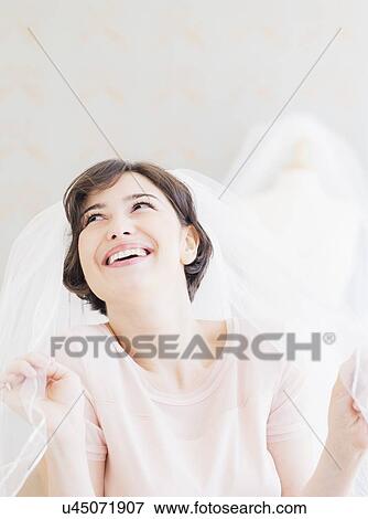 Stock Photo - Portrait of woman trying on wedding veil. Fotosearch