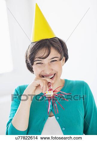 Portrait of woman wearing party hat and holding party horn blower View Large Photo Image Picture - Portrait of woman wearing party hat and holding party horn blower. Fotosearch