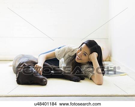 Picture - Portrait of woman with dog lying on floor. Fotosearch