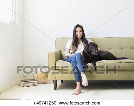 Portrait of woman with dog sitting on sofa View Large Photo Image Stock Image - Portrait of woman with dog sitting on sofa. Fotosearch