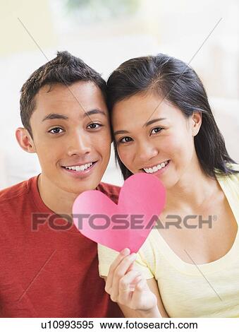 Portrait of young couple holding paper heart View Large Photo Image Stock Photography - Portrait of young couple holding paper heart. Fotosearch