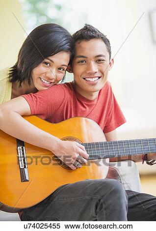 Portrait of young couple, man holding guitar View Large Photo Image Stock Photography - Portrait of young couple, man holding guitar. Fotosearch