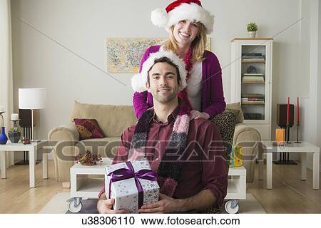 Stock Image - Portrait of young couple wearing santa hats. Fotosearch