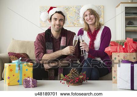 Portrait of young couple wearing santa hats drinking champagne View Large Photo Image Stock Image - Portrait of young couple wearing santa hats drinking champagne. Fotosearch