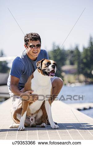 Stock Photograph - Portrait of young man posing with his dog. Fotosearch