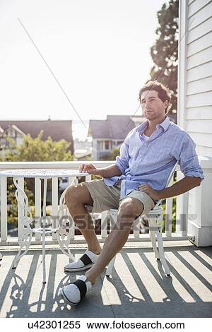 Portrait of young man relaxing on balcony View Large Photo Image Stock Photography - Portrait of young man relaxing on balcony. Fotosearch