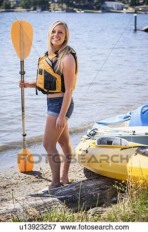 Portrait of young woman holding oar on lake shore View Large Photo Image Stock Photo - Portrait of young woman holding oar on lake shore. Fotosearch