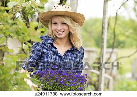 Stock Photo - Portrait of young woman holding potted flowers. Fotosearch