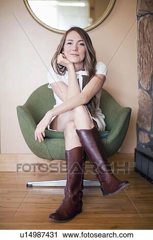 Portrait of young woman sitting on armchair View Large Photo Image Stock Image - Portrait of young woman sitting on armchair. Fotosearch