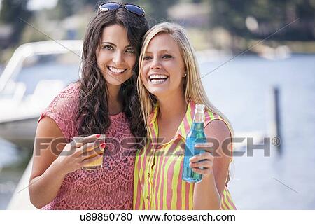 Stock Image - Portrait of young women posing with drinks. Fotosearch