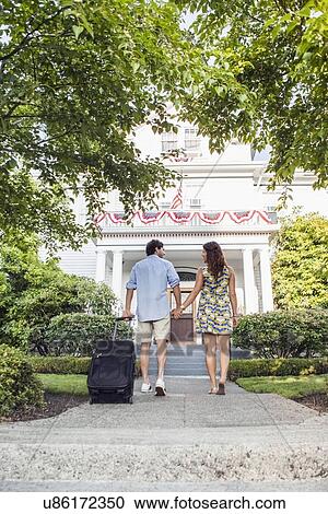 Rear view of couple walking towards hotel View Large Photo Image Stock Image - Rear view of couple walking towards hotel. Fotosearch
