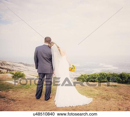 Rear view of married couple standing by sea View Large Photo Image Stock Image - Rear view of married couple standing by sea. Fotosearch
