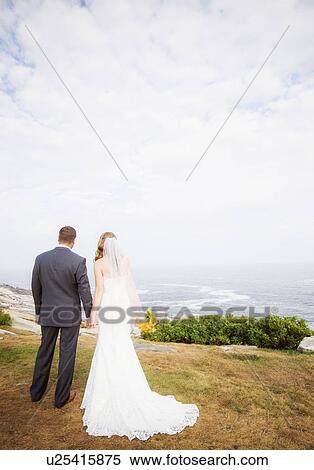 Rear view of married couple standing by sea View Large Photo Image Stock Photography - Rear view of married couple standing by sea. Fotosearch
