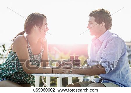 Stock Image - Side view of young man and woman looking at each other. Fotosearch