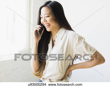Picture - Smiling young woman talking via mobile phone. Fotosearch