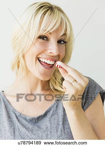 Studio portrait of blonde woman eating candy View Large Photo Image Stock Photo - Studio portrait of blonde woman eating candy. Fotosearch