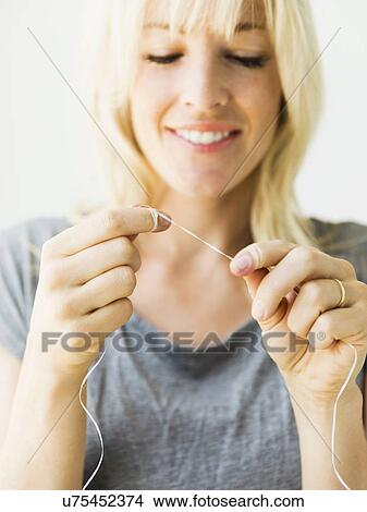 Studio portrait of blonde woman cleaning teeth with dental floss View Large Photo Image Picture - Studio portrait of blonde woman cleaning teeth with dental floss. Fotosearch