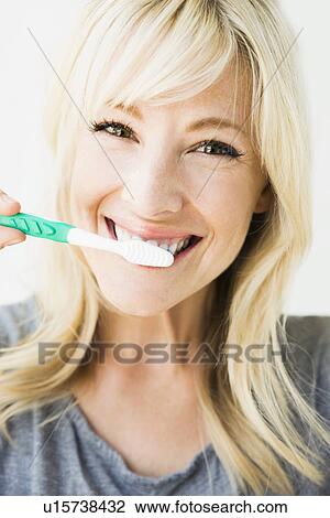 Studio portrait of blonde woman cleaning teeth View Large Photo Image Stock Image - Studio portrait of blonde woman cleaning teeth. Fotosearch