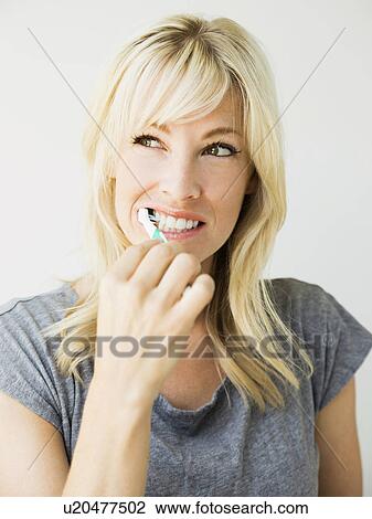 Studio portrait of blonde woman cleaning teeth View Large Photo Image Stock Image - Studio portrait of blonde woman cleaning teeth. Fotosearch