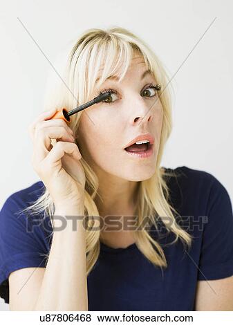 Studio portrait of blonde woman applying mascara View Large Photo Image Stock Photo - Studio portrait of blonde woman applying mascara. Fotosearch