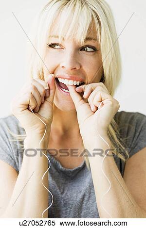 Studio portrait of blonde woman cleaning teeth with dental floss View Large Photo Image Stock Photography - Studio portrait of blonde woman cleaning teeth with dental floss. Fotosearch