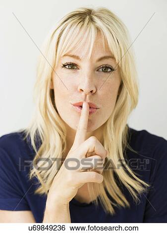 Studio portrait of blonde woman with finger on lips View Large Photo Image Stock Photograph - Studio portrait of blonde woman with finger on lips. Fotosearch