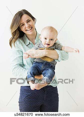 Stock Image - Studio portrait of mother holding baby boy (6-11 months). Fotosearch