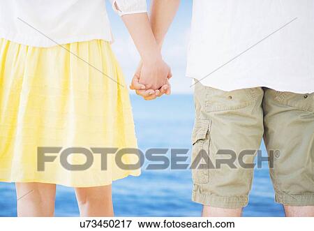 Studio Shot Mid section of couple standing and holding hands View Large Photo Image Stock Photo - Studio Shot Mid section of couple standing and holding hands. Fotosearch