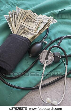 Stock Image - Studio shot of blood pressure monitor with money. Fotosearch