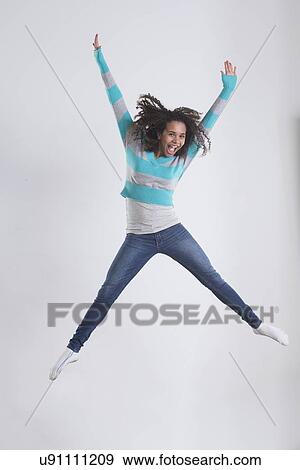 Stock Photo - Studio Shot of girl (12-13) jumping. Fotosearch