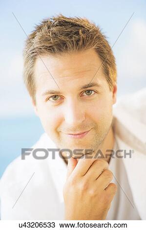 Stock Image - Studio Shot of handsome man with hand on chin. Fotosearch