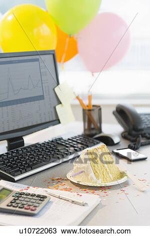 Stock Image - Studio shot of office workspace with cake and balloons. Fotosearch