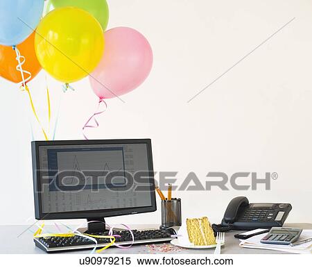 Stock Photography - Studio shot of office workspace with cake and balloons. Fotosearch