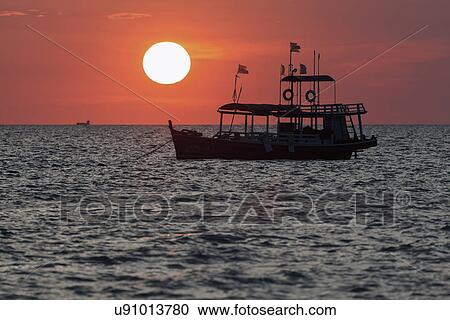 Stock Image - Trawler against setting sun. Fotosearch