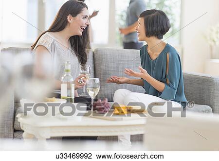 Two friends sitting on sofa and talking View Large Photo Image Stock Image - Two friends sitting on sofa and talking. Fotosearch