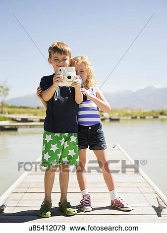 Two kids (4-5, 6-7) holding camera on pier View Large Photo Image Stock Photo - Two kids (4-5, 6-7) holding camera on pier . Fotosearch